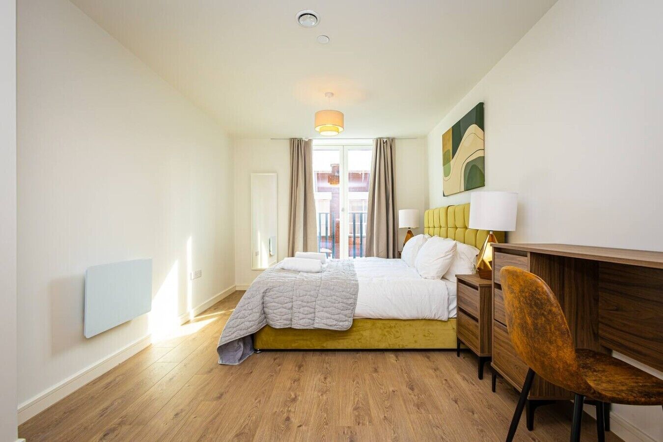 A hotel room with a bed, bedside table, chair, and a view of the outside.