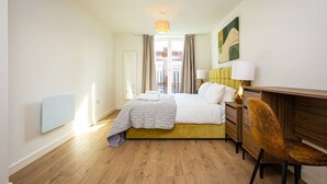 A hotel room with a bed, bedside table, chair, and a view of the outside. - Birmingham City Retreat No 121 (Birmingham)