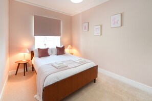 A bedroom with a bed, bedside lamps, a window with blinds, and framed pictures on the wall. - Hobsland Farm nr Prestwick Airport (Monkton)