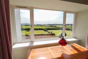 Een kamer met een groot raam met uitzicht op een groen landschap.