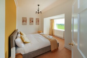 A bedroom with a large bed, a chandelier, a window with curtains, and artwork on the wall. - Hobsland Farm nr Prestwick Airport (Monkton)