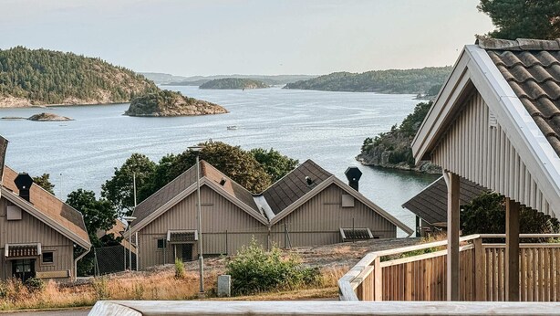 A coastal property with multiple wooden buildings, a wooden deck, and a view of the sea and distant islands. - 5 Star Holiday Home in Uddevalla (Uddevalla)