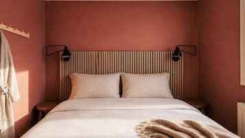 A bedroom with a bed, two bedside lamps, a headboard with vertical lines, and a bedside table.