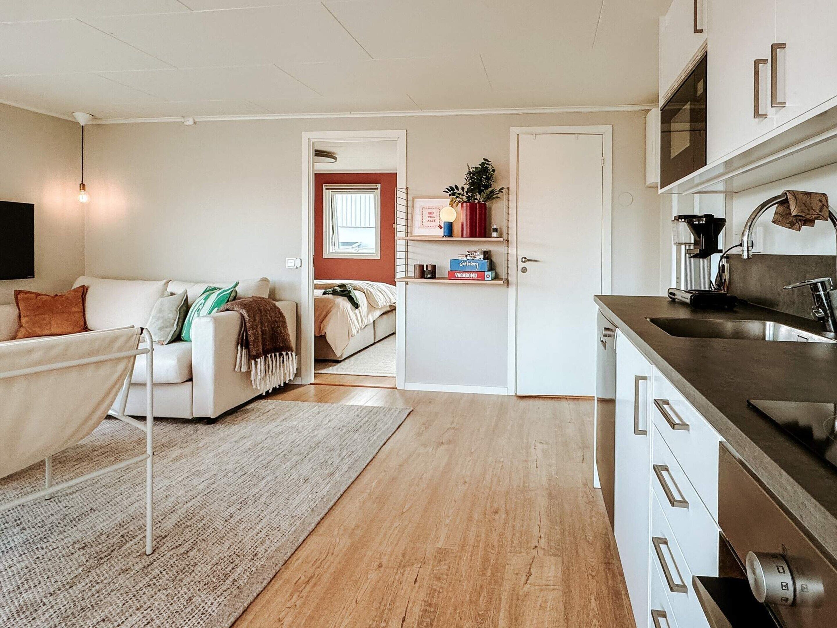 A modern kitchen with a stainless steel sink and a dining area with a white table and chairs.