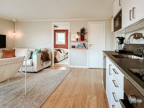 A modern kitchen with a stainless steel sink and a dining area with a white table and chairs.