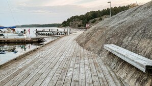 A wooden pier extending into calm water with boats docked, surrounded by a hilly landscape. - 5 Star Holiday Home in Uddevalla (Uddevalla)