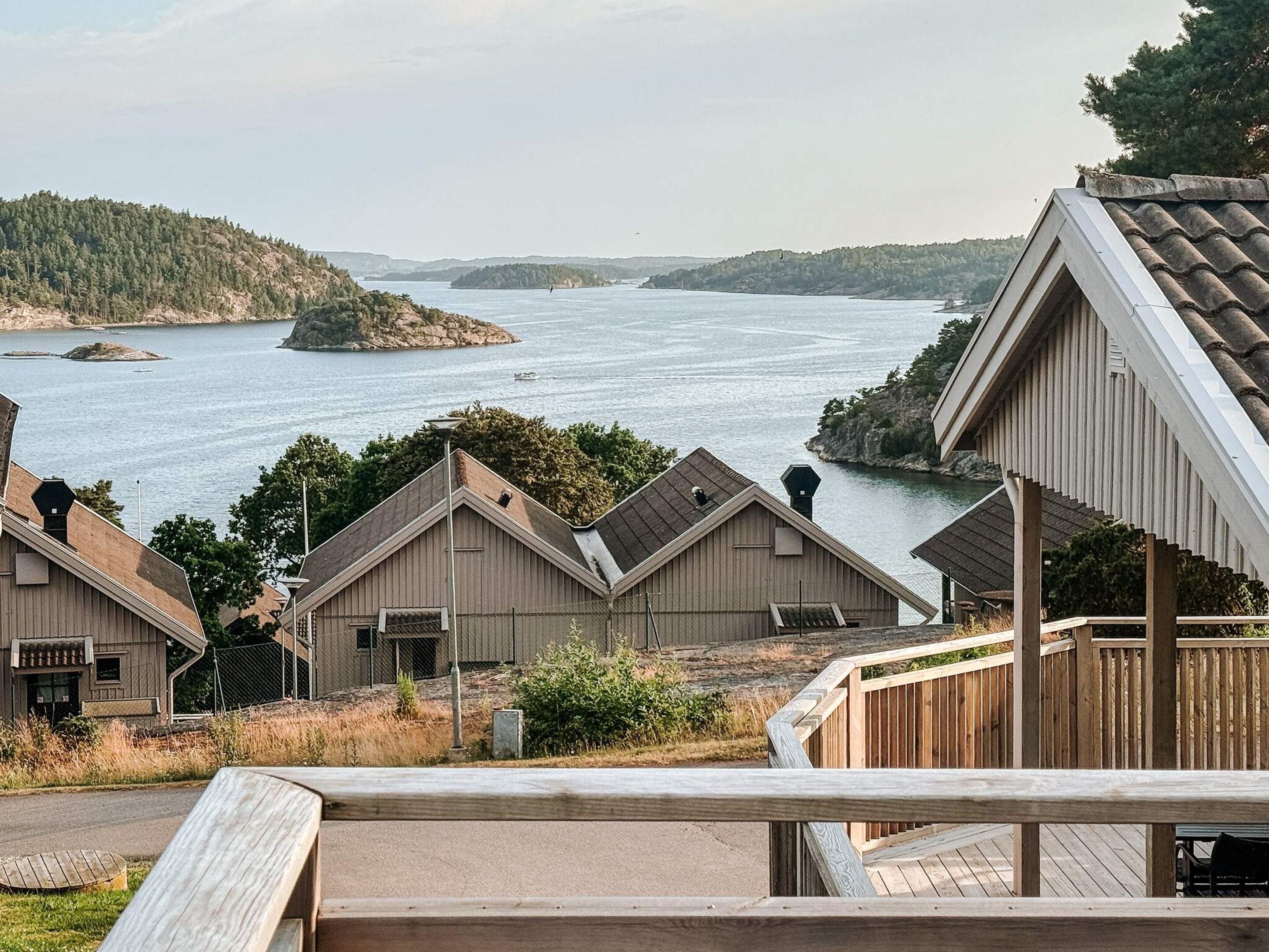 A coastal property with multiple wooden buildings, a wooden deck, and a view of the sea and distant islands.