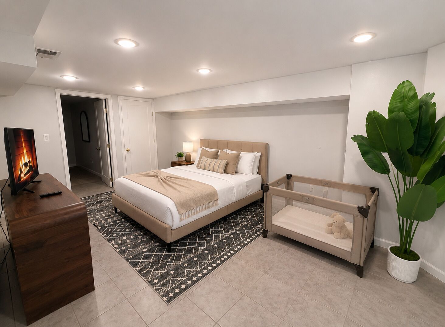 A modern bedroom with a bed, bedside table, lamp, and a small seating area.