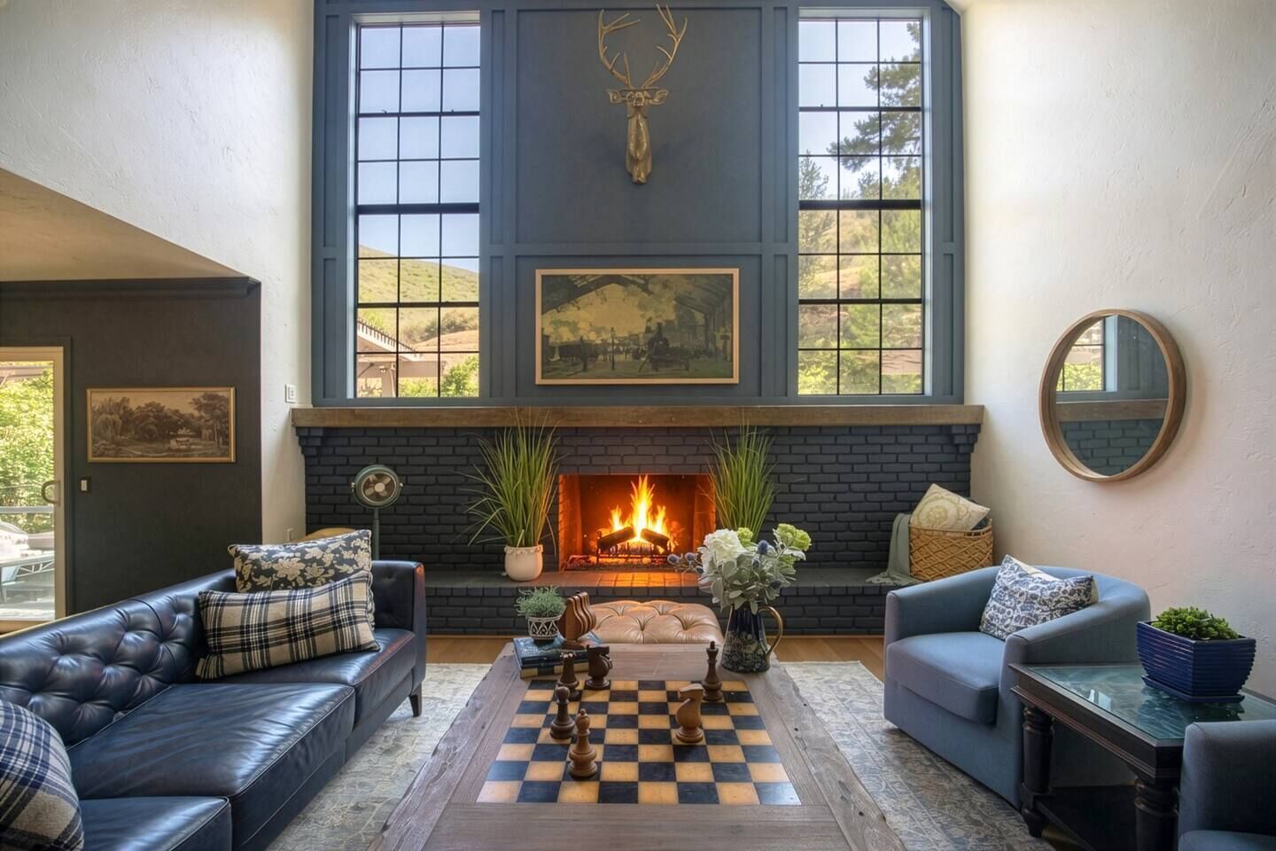 A living room with a fireplace, leather sofas, a chessboard, and a large window.