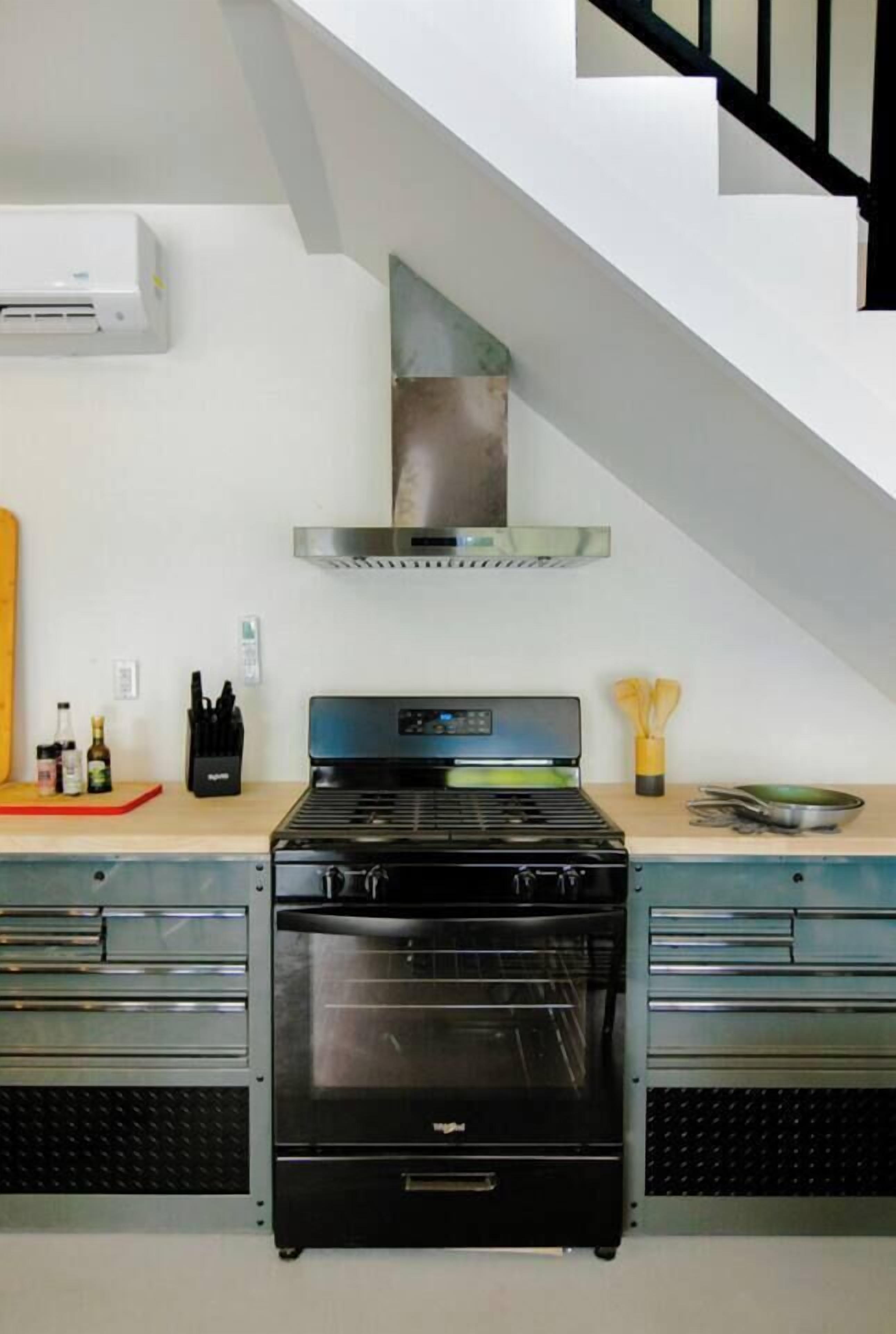A kitchen with a built-in oven, a stainless steel range hood, and a wooden countertop.