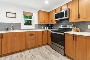 Una cucina moderna con mobili in legno, forno in acciaio inossidabile, microonde e una finestra con vista sugli alberi.