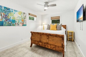 A bedroom with a bed, a ceiling fan, a window with a view, a painting on the wall, and a television mounted on the wall. - Harbor Haven - New to Rental Market - 3 Bedroom near Bayou (Santa Rosa Beach)