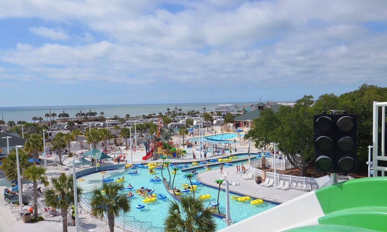 A water park with multiple pools, slides, and a view of the ocean.