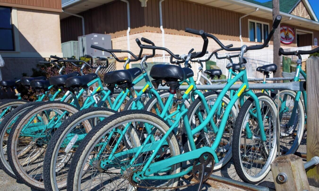 A row of turquoise bicycles parked in a metal rack.