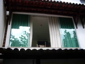 A room with a large window, a visible ceiling light, and a brick wall. - Angra TOP View of the Mountain, Beach, Pool, Marina (Angra dos Reis)