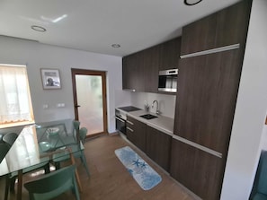 A modern kitchen with dark wood cabinets, a stainless steel sink, and an oven. - Coral House (Viana do Castelo)