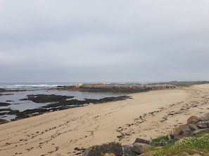 A beach with rocky outcrops, a wooden walkway, and a stone wall. - Coral House (Viana do Castelo)