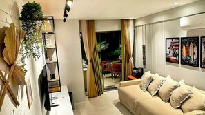A modern living room with a sofa, a dining area with a table, and a view of the outdoors. - Casa Dez Guarajuba  (Camaçari)
