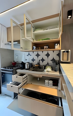 A compact kitchen with integrated storage, a built-in oven, and a patterned backsplash. - Casa Dez Guarajuba  (Camaçari)