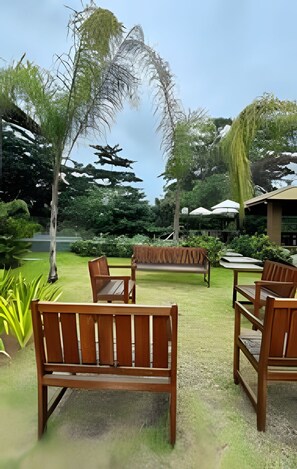A garden with wooden benches and a covered seating area. - Casa Dez Guarajuba  (Camaçari)