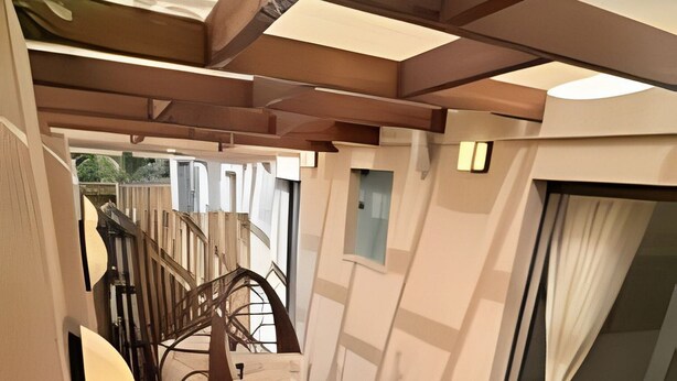 A narrow corridor with a wooden bench and a window on one side. - Casa Dez Guarajuba  (Camaçari)