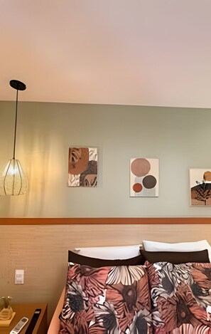 A hotel room with a bed, a nightstand, and wall art. - Casa Dez Guarajuba  (Camaçari)