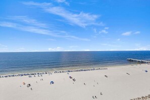 Une plage avec une jetée qui s’avance dans l’eau, un ciel dégagé et une rive sablonneuse.