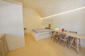 Un dormitorio con una cama, una mesa de comedor de madera y sillas.