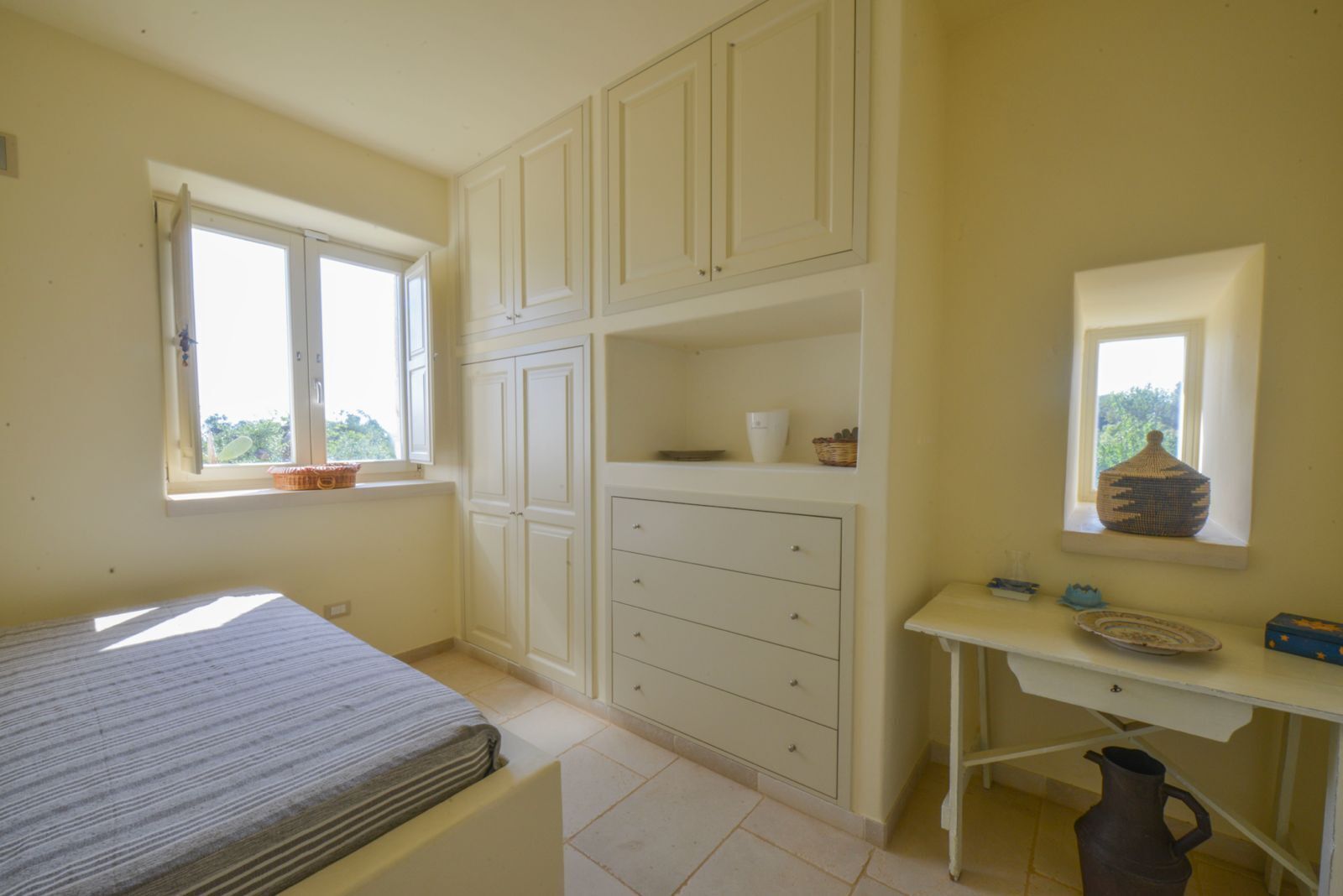 A bedroom with a bed, a dresser, a window, and a mirror.
