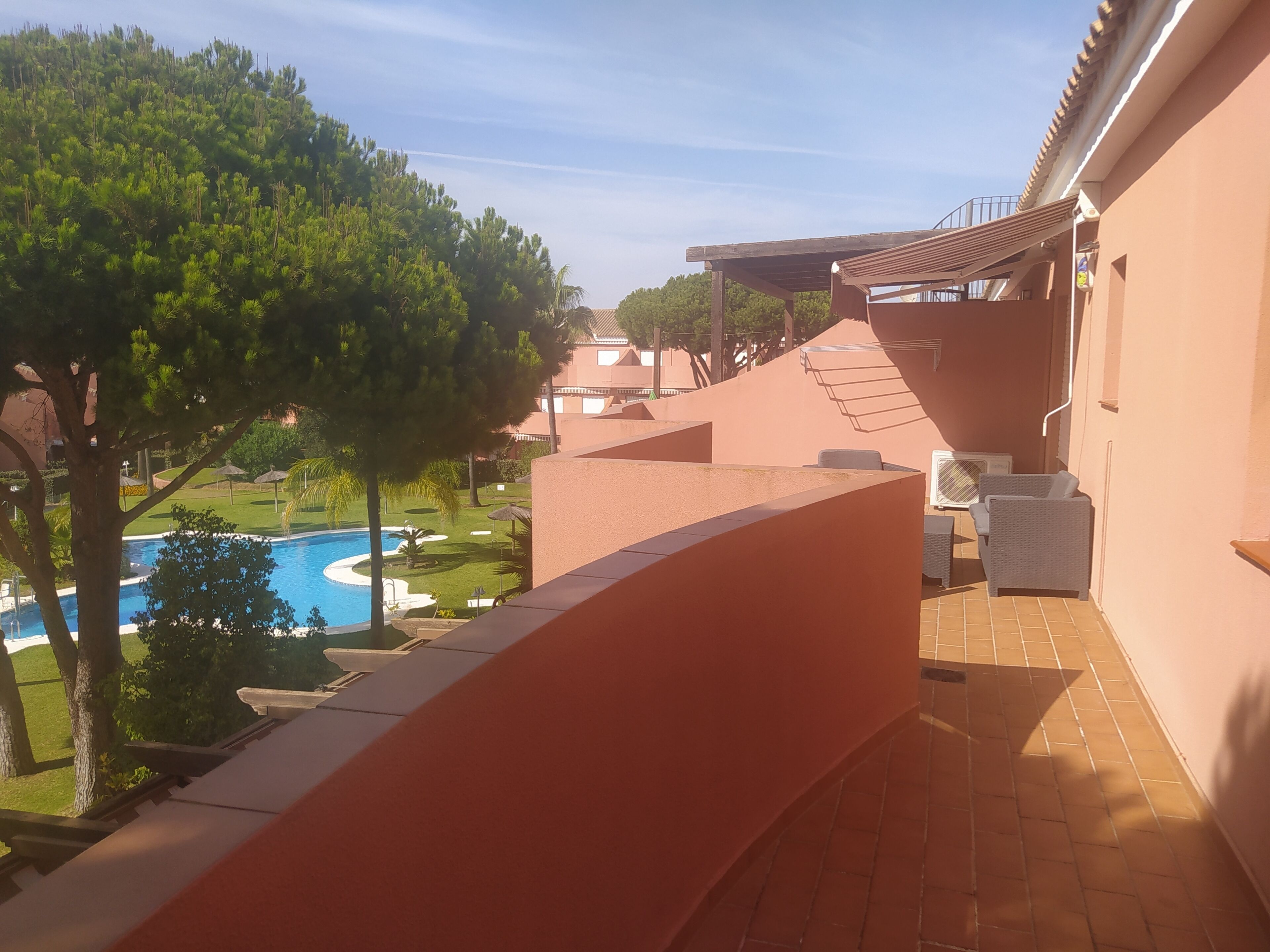 A balcony with a view of a swimming pool and a landscaped area.