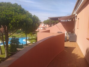 Un balcó amb vista a una piscina i una zona enjardinada.