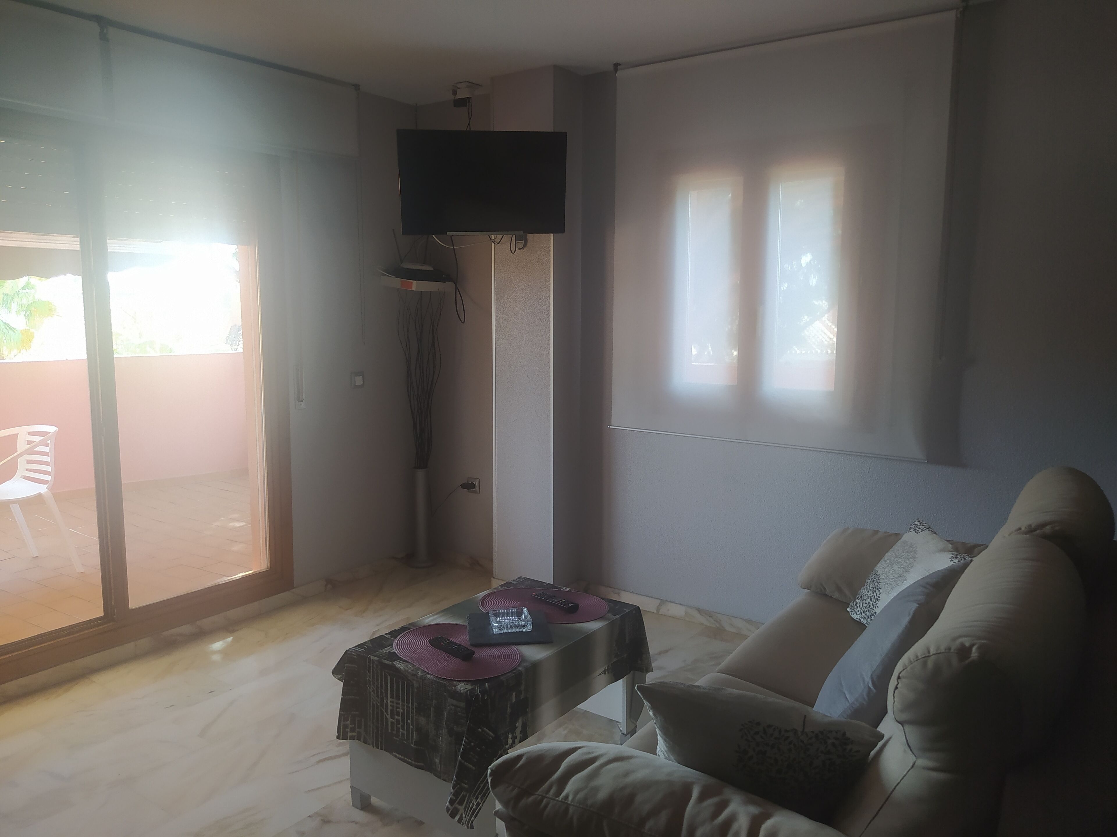 Ett vardagsrum med en soffa, ett soffbord och en tv som är monterad på väggen.