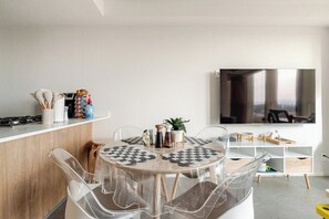 Una cocina moderna con una mesa redonda, sillas transparentes y un televisor montado en la pared.