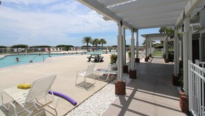 A covered pool area with lounge chairs, a table, and a view of the pool. - Welcome to Your Beachside Escape Tucked Away on the Serene Fort Morgan Peninsula (Gulf Shores)
