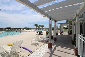 A covered pool area with lounge chairs, a table, and a view of the pool. - Welcome to Your Beachside Escape Tucked Away on the Serene Fort Morgan Peninsula (Gulf Shores)