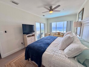 Ein Schlafzimmer mit einem Bett, einem Fernseher, einem Deckenventilator und Meerblick.