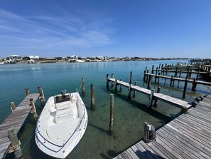 A boat docked at a pier with clear water, wooden walkways, and houses in the background. - Coastal Comfort w/ Pool + Easy Beach Access 2br/2ba (Orange Beach)