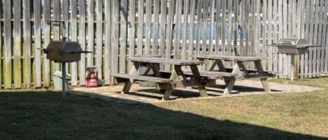 Una cerca de madera, mesas de picnic y un pabellón en un parque.