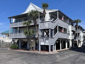 A multi-story hotel with balconies, a covered entrance, and a sign indicating 'VILLAGE.' - Coastal Comfort w/ Pool + Easy Beach Access 2br/2ba (Orange Beach)
