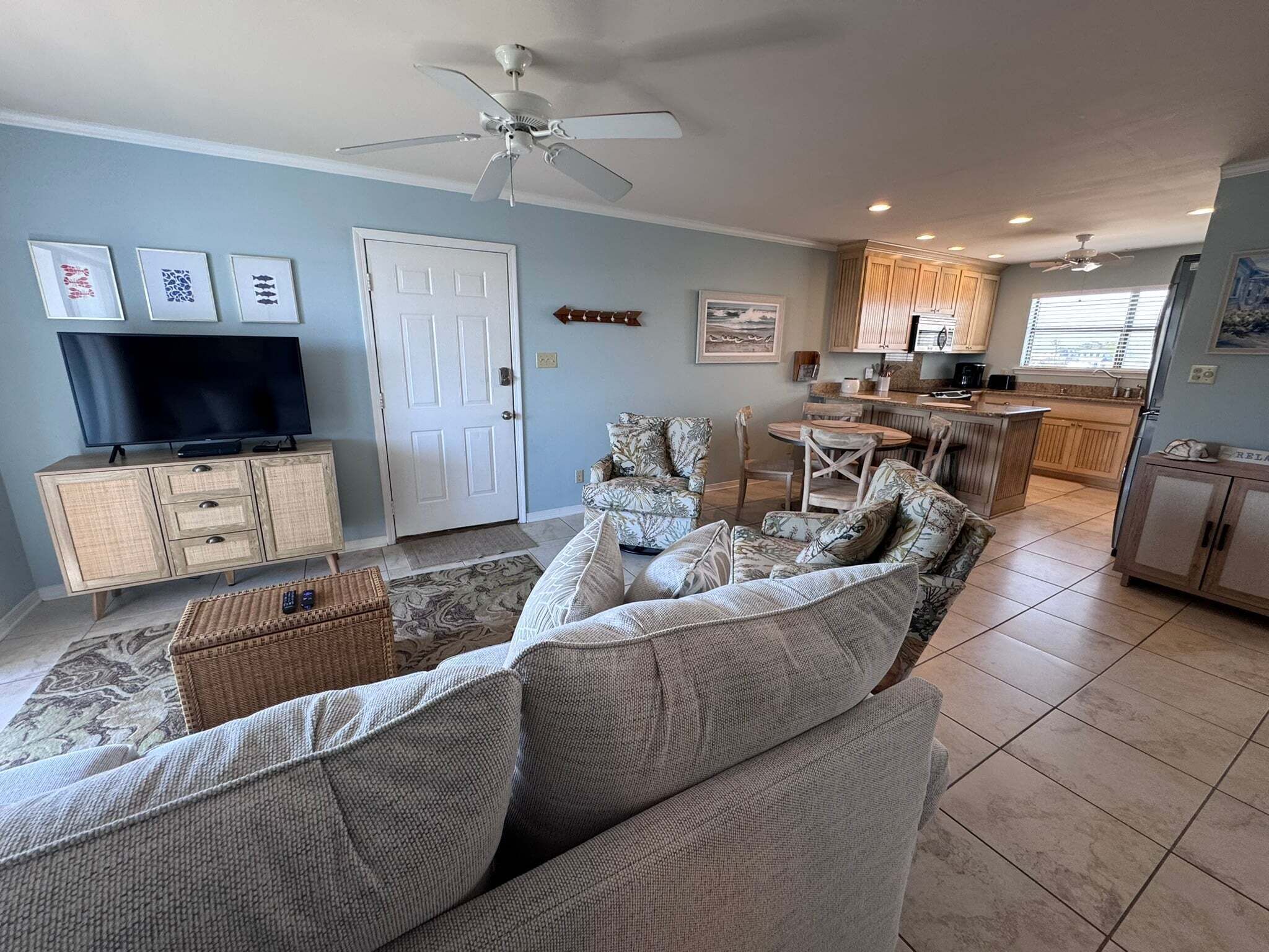 A living room with a sofa, TV, and a ceiling fan.