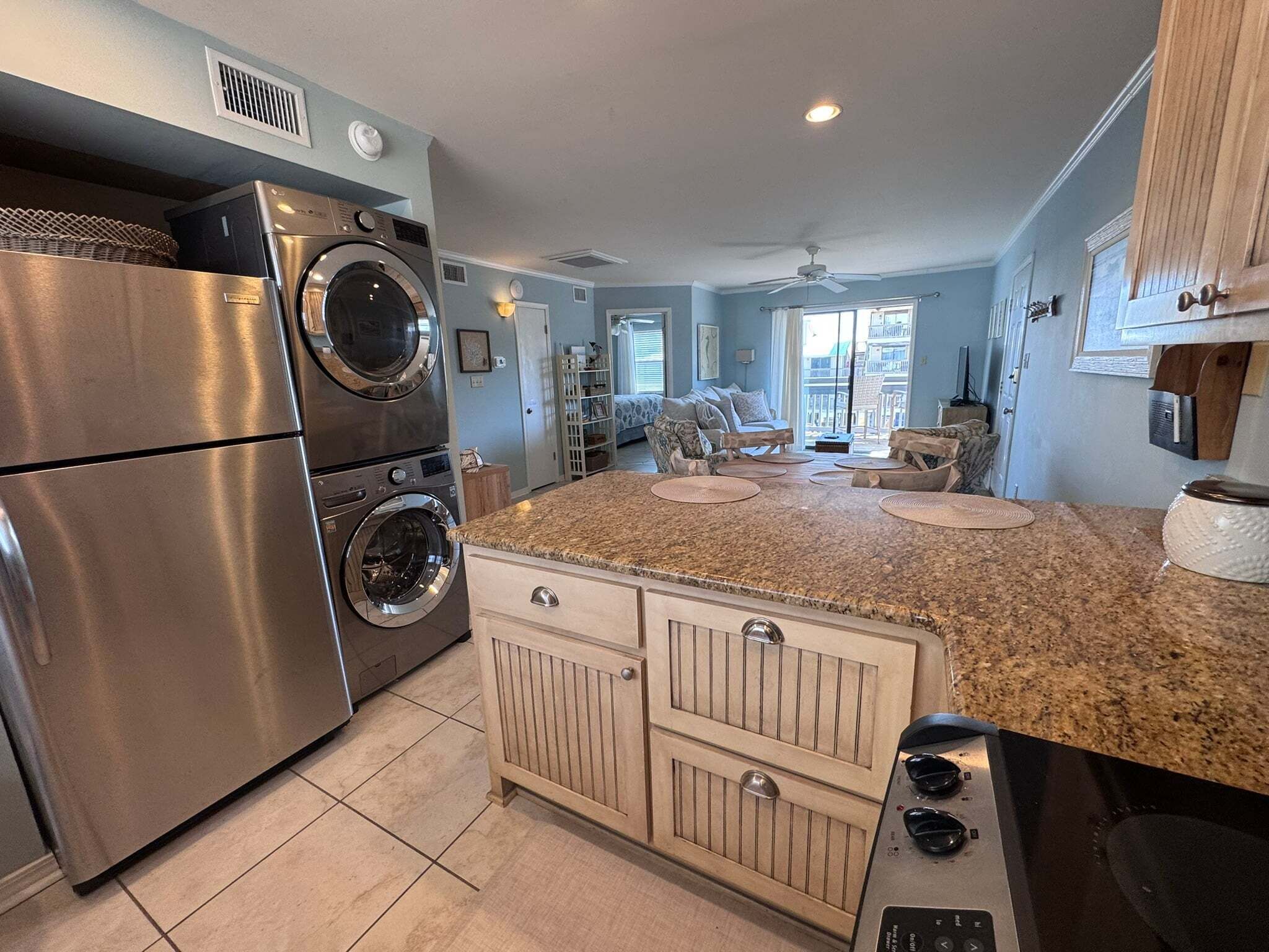 A kitchen with stainless steel appliances, a granite countertop, and a view to the living area.