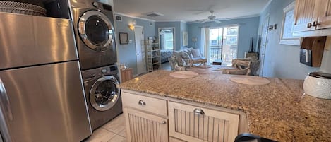 A kitchen with stainless steel appliances, a granite countertop, and a view to the living area.