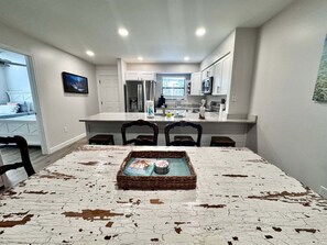 A dining area with a table, chairs, and a tray with items. - Welcome to This 2br/2ba Relaxing Coastal Escape (Orange Beach)