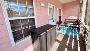 A covered patio with a grill, a door, and a seating area with chairs. - Welcome to This 3br/2ba Charming Coastal Cottage (Gulf Shores)