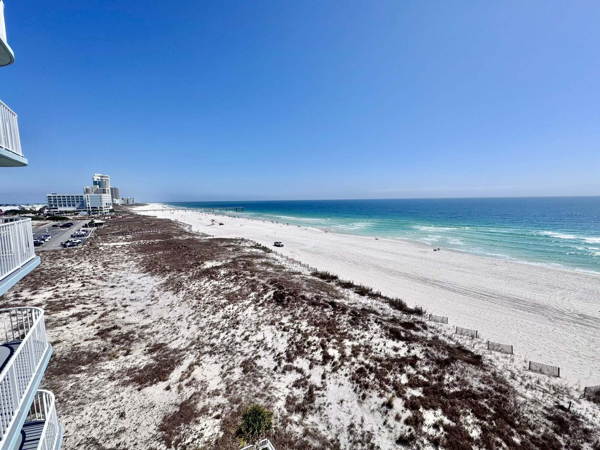 A beach with a clear view of the ocean, a sandy shore, and buildings in the background.