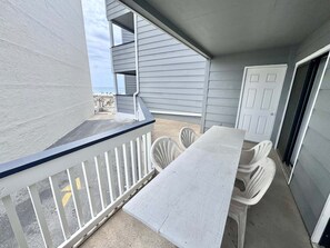 A balcony with a white railing, a table, and chairs, overlooking a beach. - Gulf Shores Getaway! 2BR Pool Walk to Beach Pet Friendly (Gulf Shores)