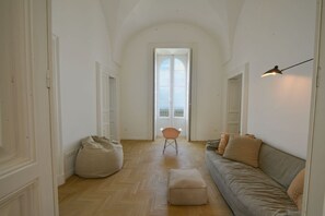 A spacious hallway with a high ceiling, a sofa, a bean bag, and a chair. - White Horizon Ostuni – Luxury Home in Center (Puglia)