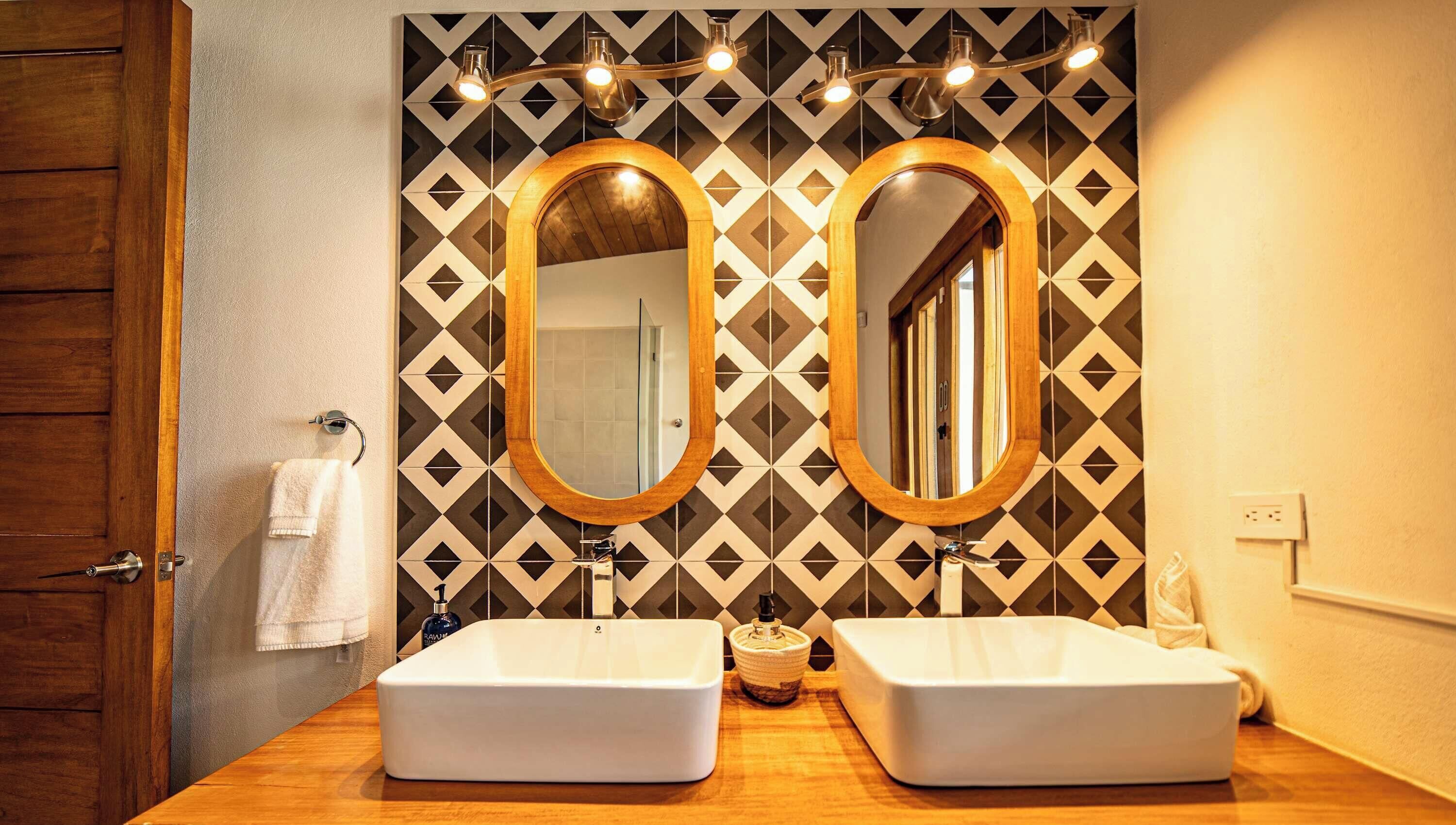 Une salle de bain avec deux lavabos, une porte en bois et un mur orné de motifs.