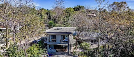 Une maison à deux étages entourée d’arbres.