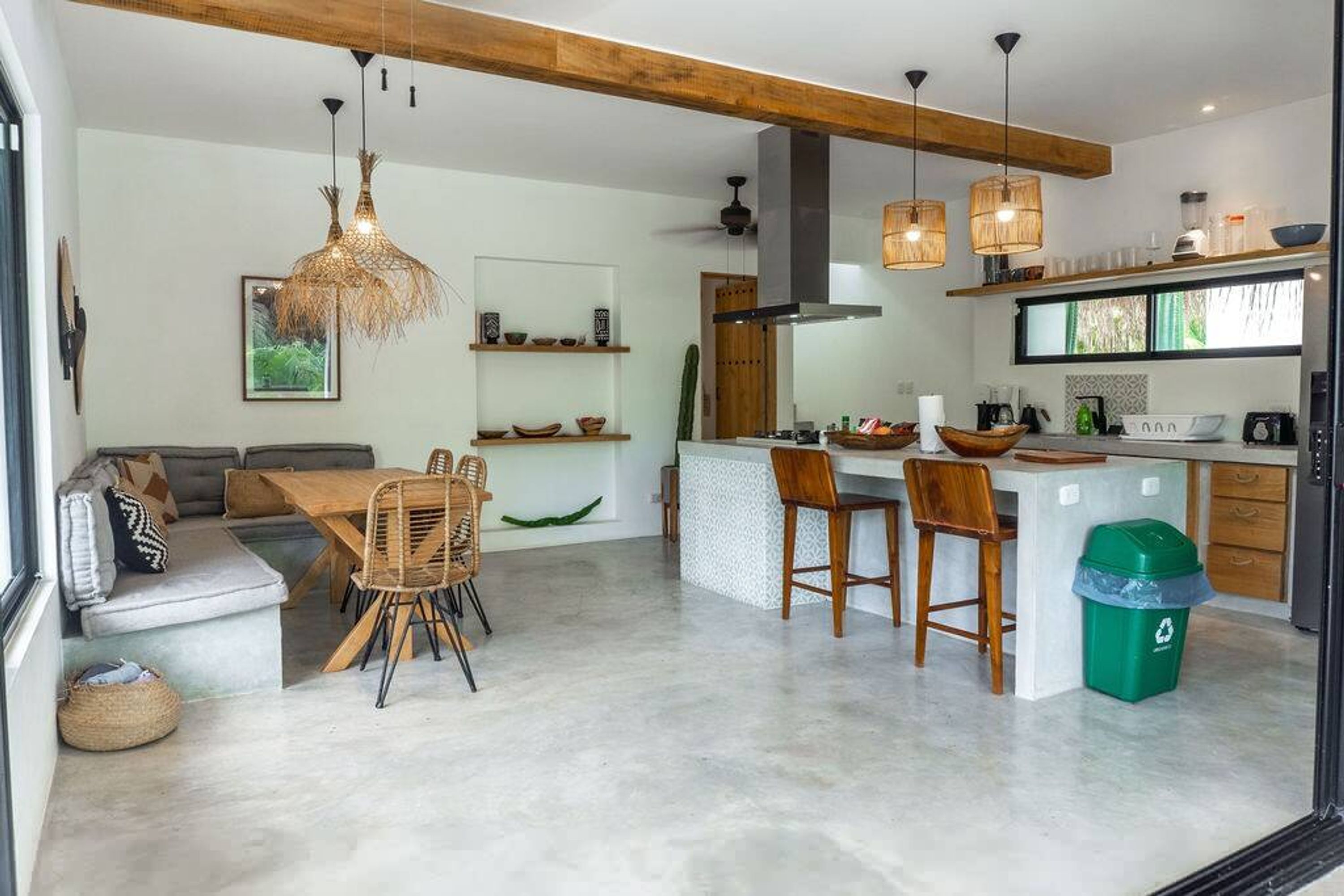 Eine moderne Küche mit einer zentralen Kochinsel, Barhocker und einem Essbereich mit einer Couch und Stühlen.